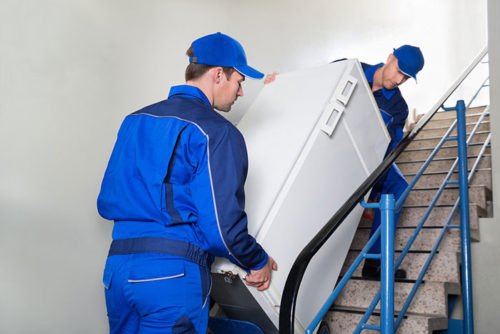 Movers carrying a fridge up a set of stairs